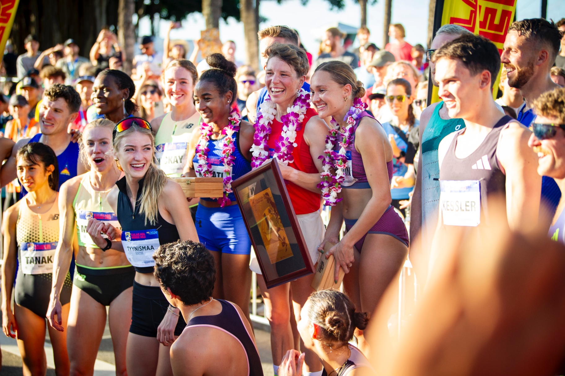 Elite athletes celebrating with lei at the Kalakaua Merrie Mile finish line